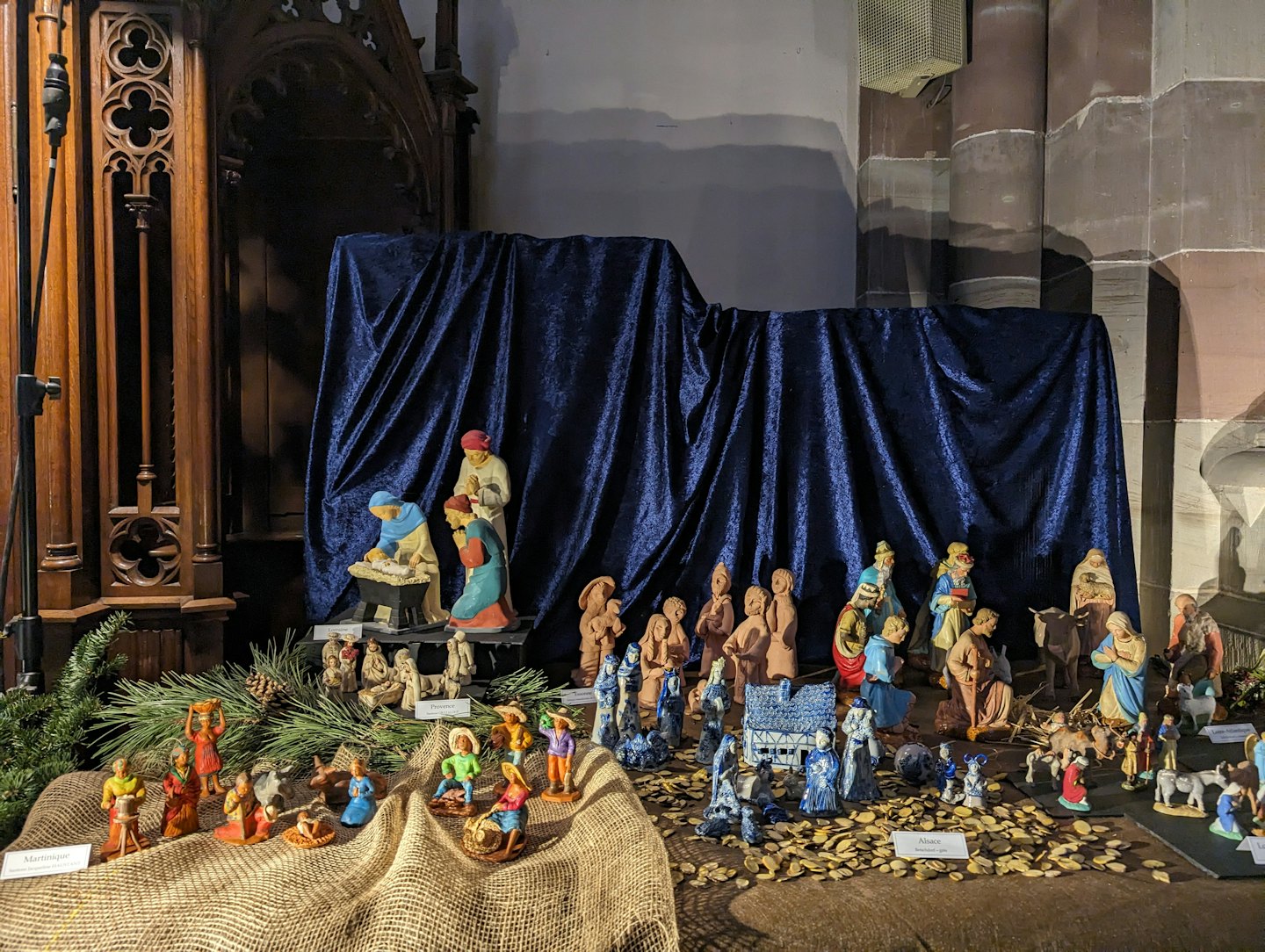 Dettagliate statuine in ceramica del presepe esposte su juta e trucioli di legno.